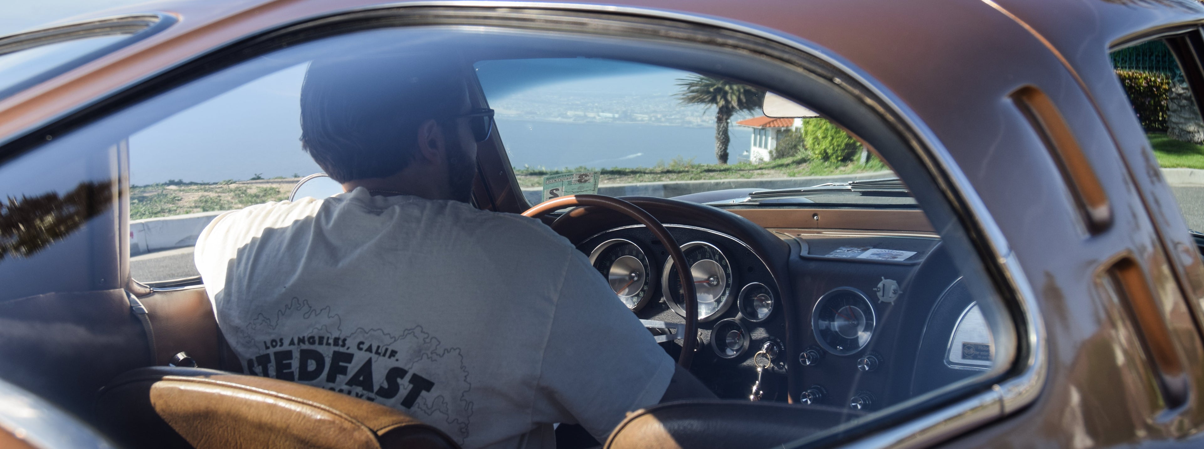 Man wearing cream color Stedfast tee in a brown 1963 corvette. Automotive lifestyle photo
